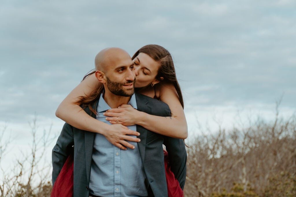 couple piggy back ride for engagement photoshoot in the mountains