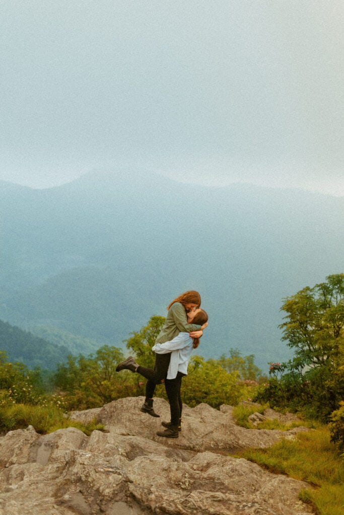 couple kissing on mountaintop after proposal