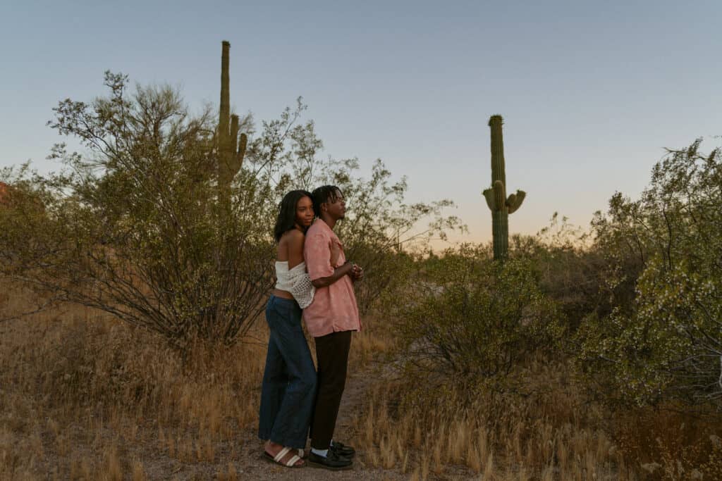 couple holding each other at sunset in front of cacti for their engagement photos in Arizona