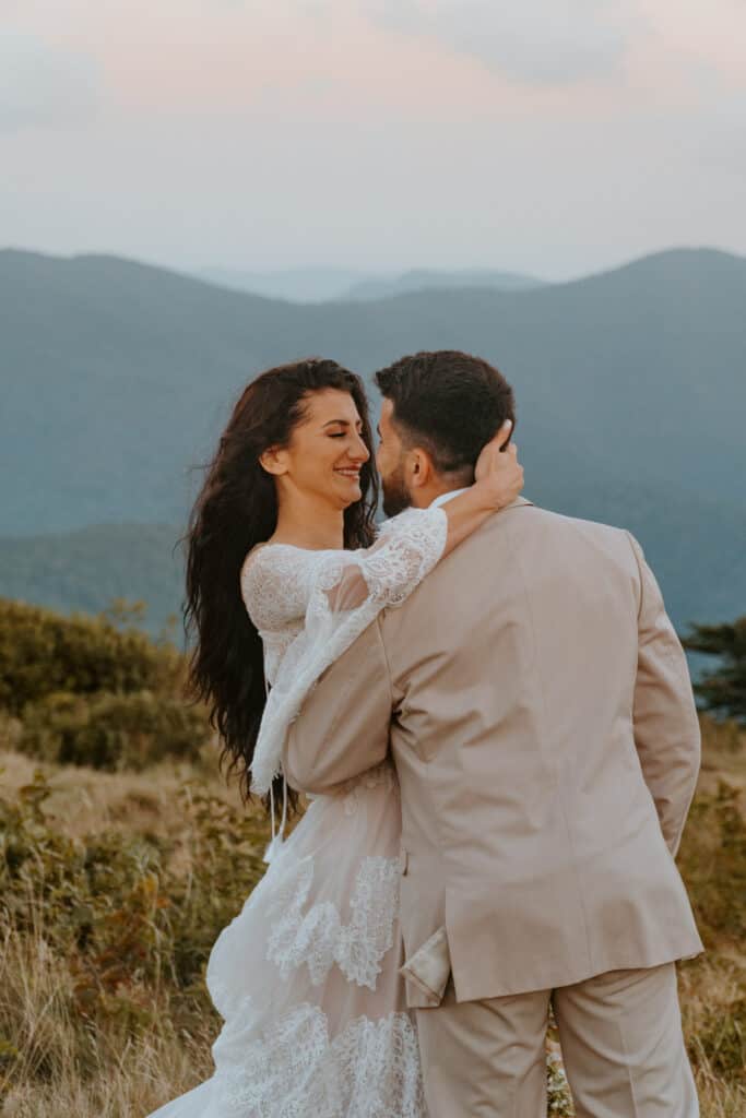 wedding couple embracing smiling at each other on top of Roan mountain for their elopement