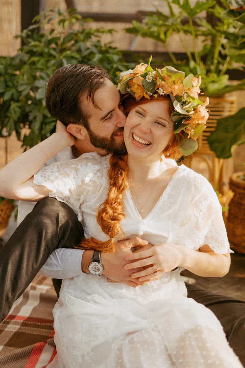 groom kissing brides cheek in greenhouse aframe airbnb
